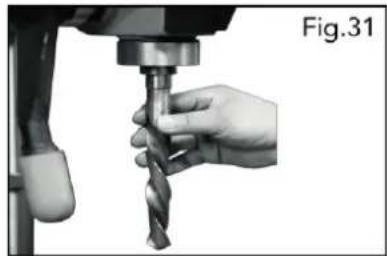 Close-up of a hand using a drill bit on a machine, labeled Fig.31 (no text on the drill bit itself)