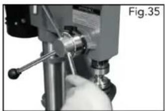 Close-up of a hand operating a mechanical drill bit with a tool, labeled Fig.35 (no text or symbols on the object itself)