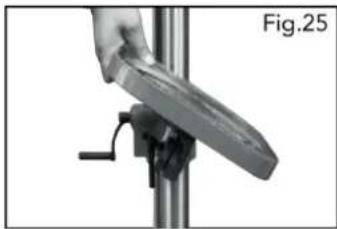 Close-up of a hand holding a metallic object mounted on a vertical stand, labeled Fig.25 (no text or symbols on the object itself)