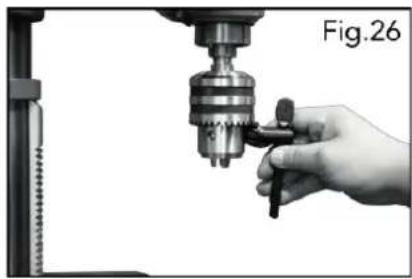 Close-up of a hand operating a drill press with a tool, labeled Fig.26 (no text on the diagram itself)