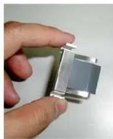 Hand holding a small metallic mechanical component (no visible text or symbols)