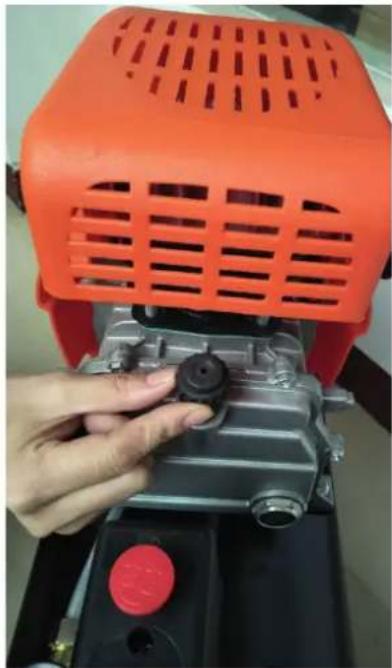 Close-up of a hand adjusting a small mechanical component with an orange filter cover (no visible text or symbols)
