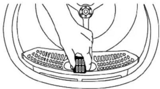 Line drawing of a hand pressing down on a circular device component (no text or symbols)