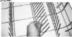 Hand holding a wire fence with diagonal bracing (no text or symbols visible)