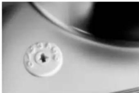 Close-up of a white circular button with a small hole, mounted on a surface (no text or symbols visible)