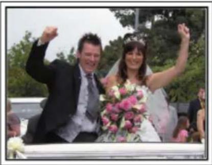 Wedding couple celebrating outdoors with raised arms and floral arrangement (no visible text or symbols)