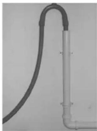 Close-up of a white PVC pipe fitting with a black curved tube attached, against a plain background (no text or symbols visible)