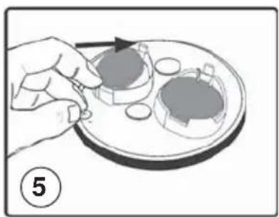 Illustration of a hand placing a small object on a tray with a circular component, no text or symbols present