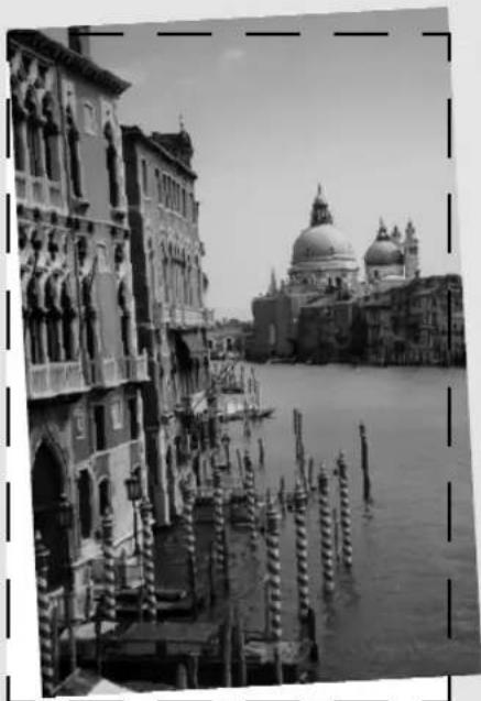Black-and-white photo of a historic canal scene with Venetian architecture and a large domed building in the background (no visible text or symbols)