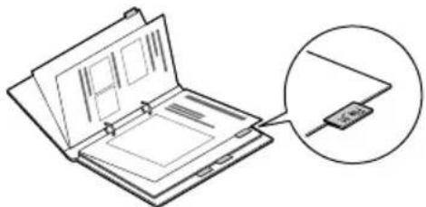 Line drawing of an open notebook with a magnified inset showing a small electronic device (no text or symbols)