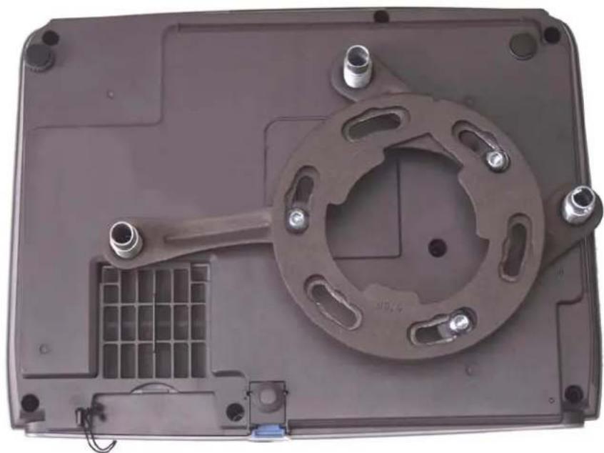 Top-down view of a mechanical device casing with a circular component and internal grid structure (no visible text or symbols)