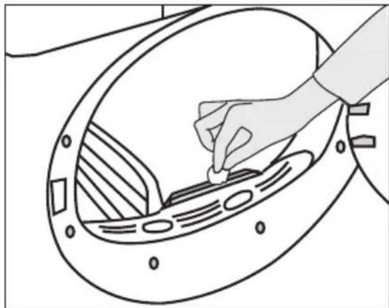 Line drawing of a hand placing a small object into a circular mechanical component (no text or symbols)