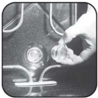 Close-up of a hand holding a small transparent object over a glass bulb, with no visible text or symbols.