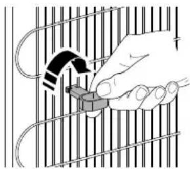 Illustration of a hand inserting a small object into a cage-like structure (no text or symbols)