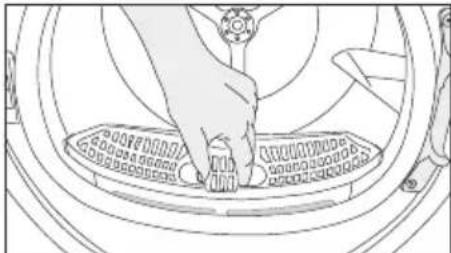 Line drawing of a hand pressing down on a circular mechanical component (no text or symbols)