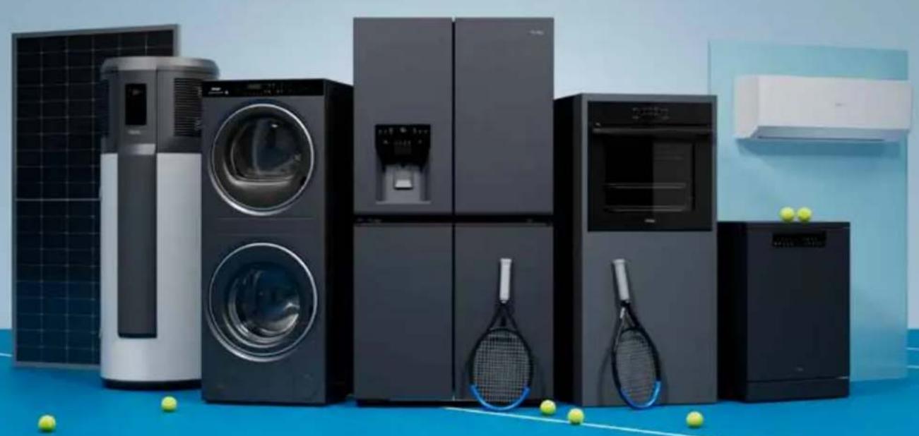 Product display of various household appliances including washing machines, refrigerators, and kitchenware on a blue mat with tennis balls (no visible text or labels)