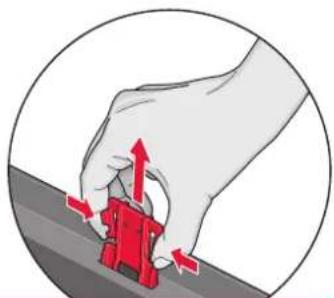 Illustration of a hand using a red tool to press or install a small object, with arrows indicating motion (no text or symbols)