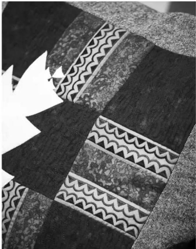 Close-up of a textured fabric with patterned and wavy sections, featuring a white stylized leaf symbol (no text or symbols present)