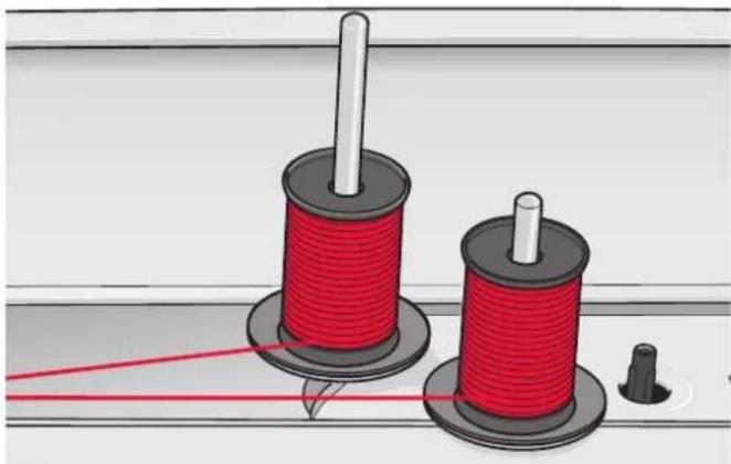 Illustration of two red thread spools with a pointer and a small protrusion, no text or symbols present