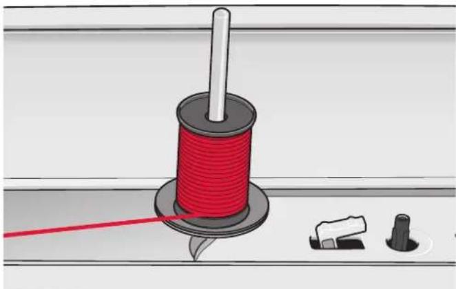 Illustration of a red thread spool with a white rod, alongside three small mechanical components (no text or symbols)