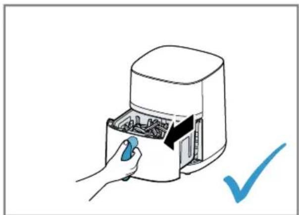 Hand placing a blue tool into an air fryer with a checkmark indicating inspection (no text or symbols on the device itself)