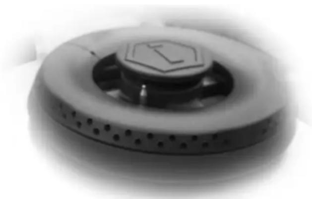 Close-up of a circular electronic device with a hexagonal top and perforated base (no visible text or symbols)