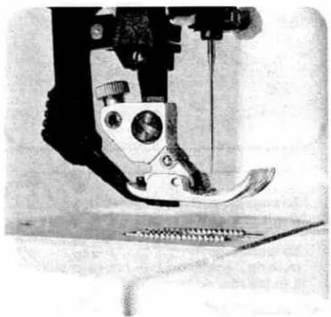 Close-up of a sewing machine needle stitching fabric (no visible text or symbols)