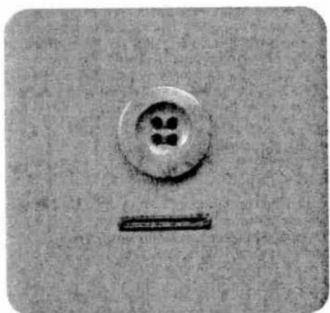 Close-up of a circular button with four dots and a horizontal bar, no visible text or symbols.