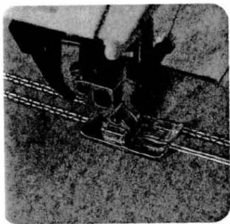 Black-and-white photo of a hand operating a large industrial machine on a conveyor belt (no visible text or symbols)
