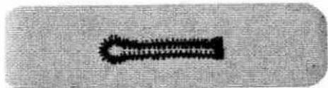 Close-up of a textured fabric surface with a dark rectangular object on the left (no visible text or symbols)