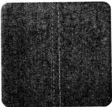 Close-up of a dark textured fabric with a vertical seam dividing it into two sections (no text or symbols visible)