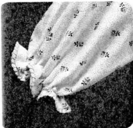 Close-up of a floral blouse with floral patterns and a small piece, resting on a textured surface (no text or symbols visible)