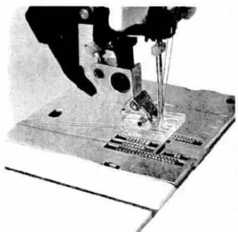 Close-up of a sewing machine needle stitching fabric (no visible text or symbols)