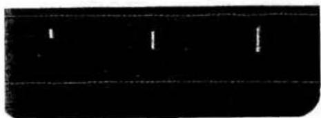 Dark rectangular object with faint horizontal lines and small white marks, no visible text or symbols