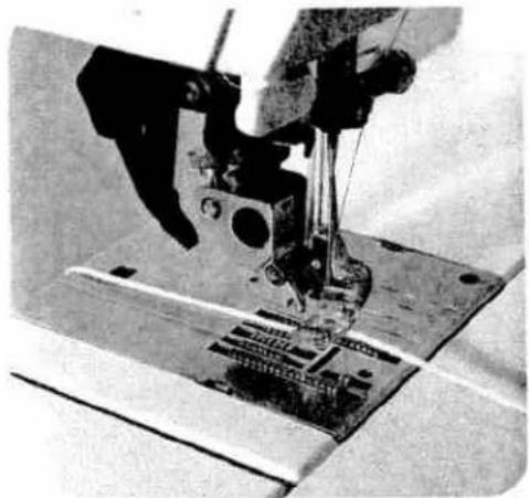 Close-up of a sewing machine needle stitching fabric (no visible text or symbols)