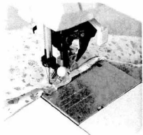 Close-up of a sewing machine needle stitching fabric, no visible text or symbols