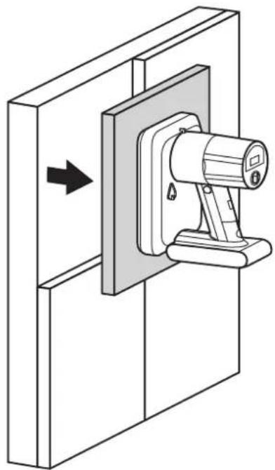 Technical line drawing of a mechanical clamp or bracket assembly mounted on a wall, with an arrow indicating direction (no text or symbols present)