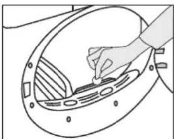 Line drawing of a hand placing a component into a circular device with internal channels (no text or symbols)