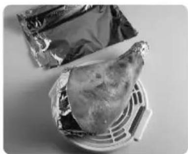 Black-and-white photo of a food item wrapped in foil, placed on a metal rack (no visible text or symbols)