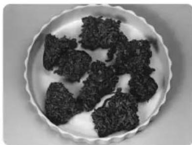 Close-up of dark, irregularly shaped food items on a white plate (no text or symbols visible)