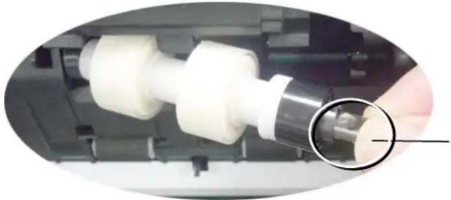 Close-up of a mechanical component being inserted into a machine, with a magnified inset showing a small cylindrical feature (no text or symbols visible)