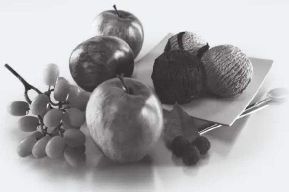 Black-and-white still life photo of assorted fruits including apples, grapes, and nuts on a white surface (no text or symbols)