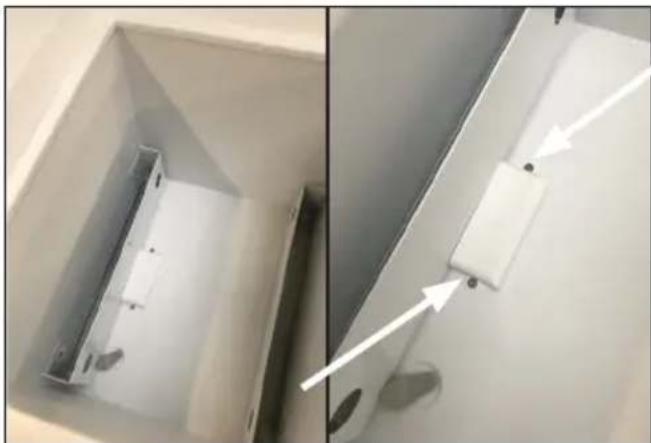 Close-up of a white cabinet interior with a metallic bracket and a white rectangular component, showing a close-up view (no text or symbols visible)
