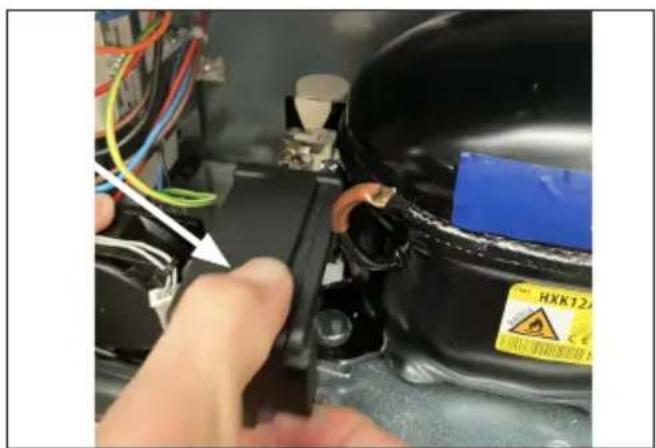 Close-up of hands adjusting a black plastic component with visible wiring and a warning label (no readable text or symbols)