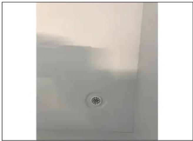 Close-up of a metallic drain outlet with a circular filter, against a plain background (no text or symbols visible)