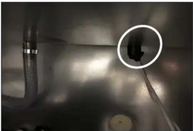 Close-up of a metallic industrial pipe with a circular inset showing a dark object, no visible text or symbols