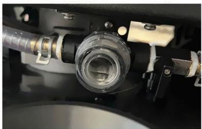 Close-up of a mechanical component with tubing and a central cylindrical component (no visible text or symbols)