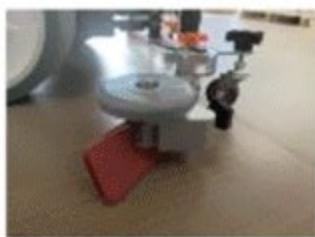 Close-up of a mechanical device with a red base and circular top, no visible text or symbols