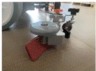 Close-up of a mechanical device with a red base and circular top, no visible text or symbols
