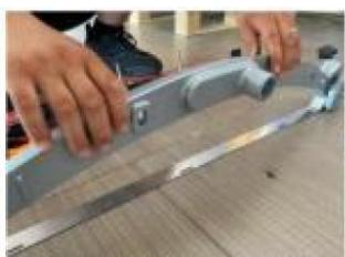 Close-up of hands assembling a metal bracket on a textured surface (no visible text or symbols)